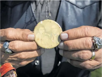  ?? Photo / AP ?? Above, Kamloops Indian Residentia­l School survivor Clayton Peters with a photograph of his parents and sister. Left, Cowichan Tribe member Benny George and his child Bowie, 3, at a vigil for lost children.