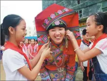  ?? FAN SHAOGUANG / FOR CHINA DAILY ?? Students help Meng Xiaomei to dress up at their primary school in Xincheng county, Guangxi Zhuang autonomous region.