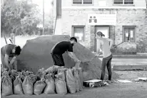  ?? Associated Press ?? n Andrea Dube, right, and John Flemming fill sandbags Friday as a precaution against the potential for more flooding in New Orleans. With debris from last weekend’s flash flood still piled up on sidewalks and their city under a state of emergency, New...