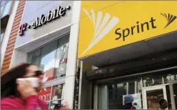  ?? AP PHOTO/MARK LENNIHAN ?? In this April 27, 2010, file photo, a woman using a cell phone walks past T-Mobile and Sprint stores in New York. T-Mobile and Sprint are trying again to combine in a deal that would reshape the U.S. wireless landscape, the companies announced Sunday.