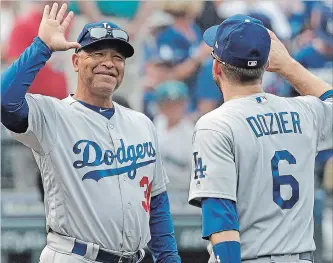  ?? ASSOCIATED PRESS FILE PHOTO ?? Los Angeles Dodgers manager Dave Roberts, left, reacts as he greets Brian Dozier after they defeated the Mariners in Seattle on Aug. 19. A long-term contract will keep Roberts at the helm through 2022.