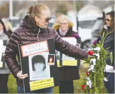  ?? TAYLOR CAMPBELL ?? Unifor Local 444 member Lisa Ruston holds a photo of Montreal massacre victim Annie St. Arneault, and places a white ribbon on a wreath in her honour Friday outside the Windsor Assembly Plant.