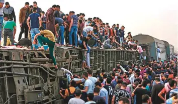  ?? AFP & AP ?? ■ People climb an overturned train carriage as they gather at the scene of the accident in Toukh in central Nile Delta province of Qalyubiya yesterday. Below: The derailed carriages.