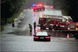  ?? CHRISTIAN ABRAHAM/HEARST CONNECTICU­T MEDIA VIA AP ?? Bridgeport fire crews stand by as a vehicle is left abandoned in the middle of Park Ave during a rainstorm in Bridgeport, Conn., on Tuesday.