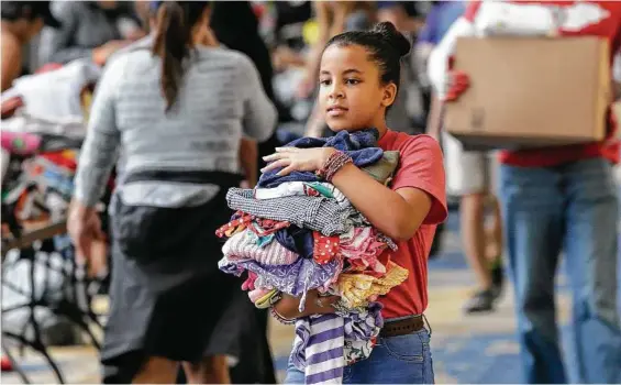  ?? LM Otero / Associated Press ?? Volunteer Asuleni Santiago, 11, carries donated clothes for storm victims at a shelter opened at Lakewood Church.