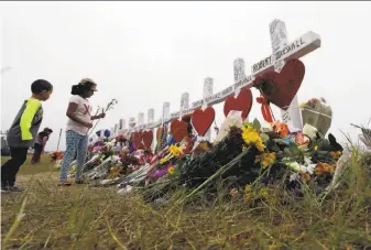  ?? Eric Gay / Associated Press ?? Alexander Osborn and Bella Araiza leave flowers at a memorial for the more than two dozen victims of the shooting attack at the First Baptist Church in Sutherland Springs, Texas.