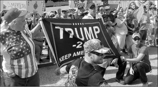  ?? MATT VOLZ / ASSOCIATED PRESS ?? Supporters of President Donald Trump hold up a banner in front of hundreds of protesters July 5 outside a rally in Great Falls, Mont.