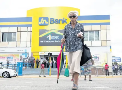  ?? GLADSTONE TAYLOR/MULTIMEDIA PHOTO EDITOR ?? An elderly woman crosses Constant Spring Road to the Half-Way Tree Transport Centre parallel to the Jamaica National Bank yesterday. It was reported the bank suffered a major cyberattac­k on its systems which affected JN Bank services.