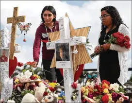  ?? JOE RAEDLE / GETTY IMAGES ?? Marissa Rodriguez (left) and Ambar Ramirez visit a memorial setup in front of Marjory Stoneman Douglas High School in Parkland, Fla., in memory of the 17 people who were shot to death on Feb. 14.