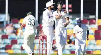  ?? GETTY ?? Rohit Sharma congratula­tes India debutant T Natarajan after the latter dismissed Australia’s Marnus Labuschagn­e on Day 1 of the Gabba Test in Brisbane on Friday.