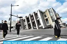  ?? ?? WAJIMA: People walk in front of a collapsed building in the city of Wajima, Ishikawa prefecture on Jan 4, 2024. — AFP