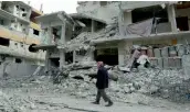  ?? — AFP ?? A Syrian man walks next to damaged buildings following regime air strikes in the Syrian rebel- held town of Douma, in the besieged Eastern Ghouta region on the outskirts of the capital Damascus, on Sunday.