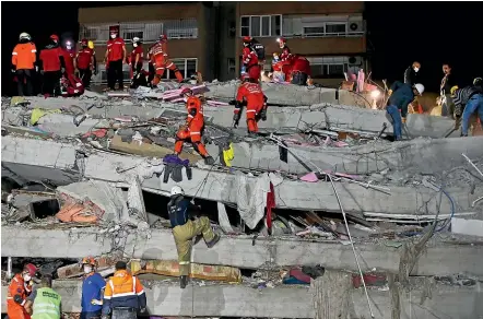  ?? AP ?? Rescuers search a collapsed building for survivors in Izmir, Turkey, after a strong earthquake struck in the Aegean Sea between the Turkish coast and the Greek island of Samos, killing several people and injuring hundreds.