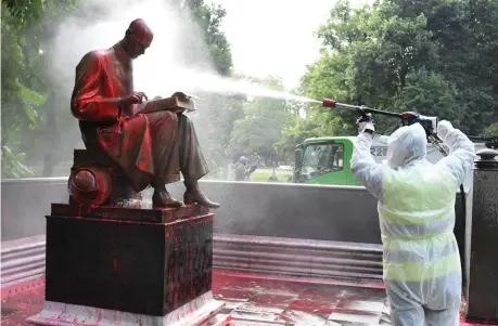  ??  ?? Nei giardini
Un operatore del Comune pulisce la statua di Indro Montanelli imbrattata di vernice sabato sera