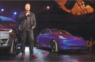  ?? Frederic J. Brown AFP/ Getty I mages ?? TESLA CEO Elon Musk speaks beside the just- unveiled Tesla Model Y, at right, in Hawthorne last month.