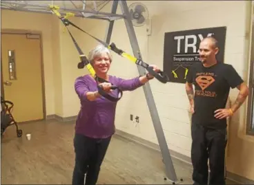  ?? BILL RETTEW JR. – DIGITAL FIRST MEDIA ?? Sue Ellen Larkin works the TRX machine, while Josh Camolli offers support, during Saturday’s MS exercise group at the YMCA of Greater Brandywine’s West Chester Branch.