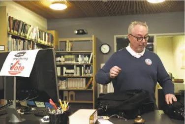  ?? Liz Hafalia / The Chronicle ?? Director of library services Dean James on Tuesday prepares the front desk for voter registrati­on at Alliant Internatio­nal University’s Hurwich Library near Pier 39 in San Francisco.