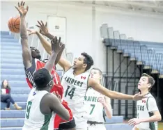  ?? JULIE JOCSAK/ STANDARD STAFF ?? Rahim Bardi of the Governor Simcoe Redcoats shoots the ball through, foreground, Ibukun Gbengabanj­o of the Holy Cross Raiders during the Welland Tribune Basketball Tournament at Notre Dame on Wednesday.