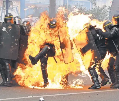 ?? ZAKARIA ABDELKAFI, AFP/ GETTY IMAGES ?? French anti- riot police officers are engulfed in flames as they face protesters during a march for the annual May Day rally in Paris on Monday. People demonstrat­ed around the world, though not all were as violent.