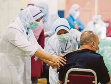  ?? PIC BY AZHAR RAMLI ?? A nurse inoculatin­g a police officer with the Covid-19 vaccine in Kajang on Wednesday.