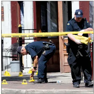  ?? AP/JOHN MINCHILLO ?? Authoritie­s pick up evidence markers Sunday at the scene of the mass shooting in Dayton, Ohio.