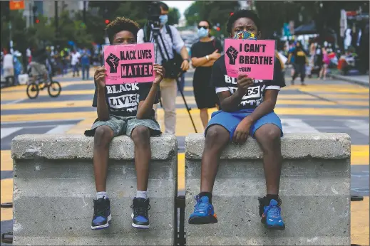  ??  ?? Tyshawn, 9, (left) and his brother Tyler, 11, of Baltimore, hold signs saying “Black Lives Matter” and “I Can’t Breathe” as they sit on a concrete barrier June 24 near a police line as demonstrat­ors protest along a section of 16th Street been renamed Black Lives Matter Plaza in Washington.
(AP/Jacquelyn Martin)