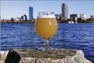  ?? CHARLES KRUPA — THE ASSOCIATED PRESS ?? A glass of Castle Island Brewing Company “Chuck” beer, a dry hopped cream ale, rests on a rock along the bank of the Charles River, Thursday in Cambridge, Mass. Leading New England breweries are competing to see who can turn the questionab­le water of...