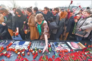  ?? NATALIA KOLESNIKOV­A / AGENCE FRANCE-PRESSE ?? Mourners place flowers and candles at a makeshift memorial honoring victims of this week’s bombing of the St. Petersburg metro that claimed 13 lives.