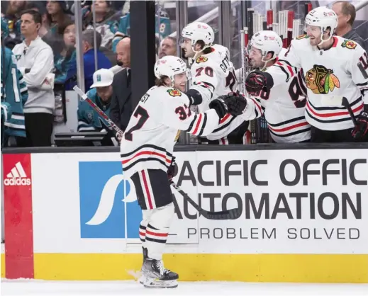  ?? JOHN HEFTI/AP ?? Blackhawks forward David Gust, a native of Orland Park, is congratula­ted after scoring his first NHL goal on his first shot Saturday against the Sharks.