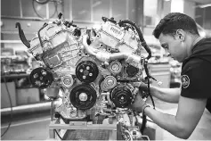  ??  ?? An employee works on a sports car engine as it moves down the production line at Group Lotus in Hethel, England, on Aug 10. — WP-Bloomberg photos