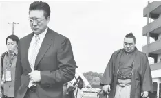  ?? — Gambar AFP ?? KETUA pasukan Isegahama (kiri) dan Harumafuji berjalan ke arah asrama di bandar Tagawa, Fukuoka untuk memohon maaf kepada Takanoiwa.