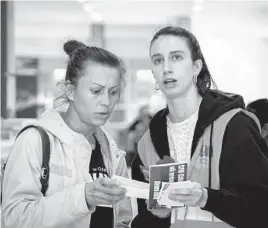  ?? CHISATO TANAKA/AP ?? Elena Trofimchuk, right, who fled Ukraine to Romania more than a month ago, helps a refugee sort out train tickets April 23 at the North Railway Station in Bucharest.