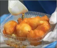  ??  ?? Victoria Psomiadis pours
honey on loukoumade­s, a greek pastry, during the food
festival.