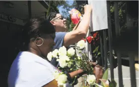  ?? Elijah Nouvelage / Special to The Chronicle ?? Barbara Branch arranges flowers and Drew Wehrstein writes a message at the makeshift memorial in Diamond Heights for slain UPS driver Mike Lefiti.