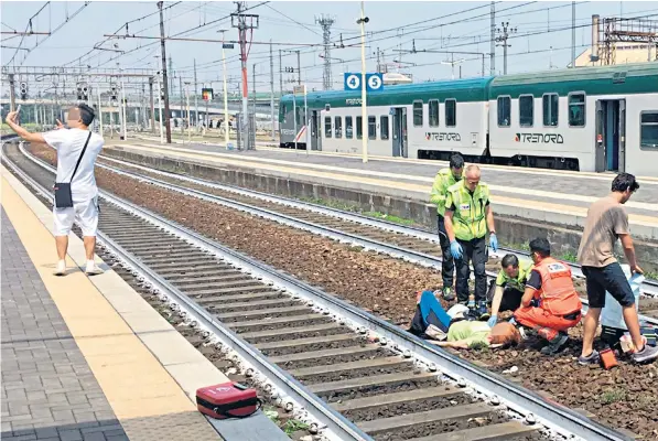  ??  ?? A local news photograph­er spotted the man posing for a selfie as medics tended an injured woman between the tracks at Piacenza’s railway station