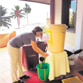  ?? COURTESY OF SANDIA NATIONAL LABORATORI­ES ?? Jen Gaudioso, senior manager of Sandia’s Internatio­nal Biological and Chemical Threat Reduction program, washes her hands in bleach before entering a hotel for meetings with U.S. aid organizati­ons in Liberia.