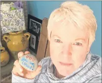  ?? LESLIE HALL VIA AP ?? In this May 12, 2017 photo provided by Leslie Hall, Hall holds a painted rock at her home in Cape Cod, Mass., that she found while fighting breast cancer.