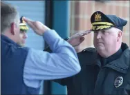  ??  ?? West Chester police Detective Scott Whiteside, left, salutes Chief James Morehead before walking out on his last day of work.