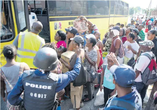  ?? PHOTOS BY GLADSTONE TAYLOR/MULTIMEDIA PHOTO EDITOR ?? Policemen urge anxious commuters to observe social distancing guidelines before entering a Jamaica Urban Transit Company bus on East Queen Street, Kingston, last Saturday. They said they were left stranded after the 3 p.m. curfew deadline having waited for buses and taxis for at least two hours.