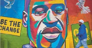  ?? MONTINIQUE MONROE/NEW YORK TIMES ?? A man walks past a mural in Houston depicting George Floyd, whose death touched off a national debate over race and policing in 2020.