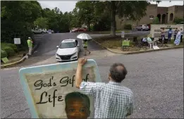  ?? DAVID GOLDMAN — THE ASSOCIATED PRESS ?? Anti-abortion protester Steven Lefemine holds a sign May 27as the anti-abortion group A Moment of Hope, wearing green vests, tries to talk with patients arriving for abortion appointmen­ts at Planned Parenthood in Columbia, S.C.