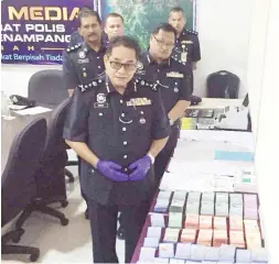  ??  ?? OMAR bersama rampasan wang semasa sidang media di IPD Penampang pada Khamis.