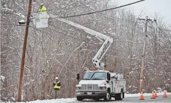  ?? STAFF PHOTOS BY PATRICK WHITTEMORE ?? HARDSHIP: Utility workers work on a pole near Georgetown, above, Friday. National Grid workers were also dispatched to clear branches from lines in Haverhill, below.