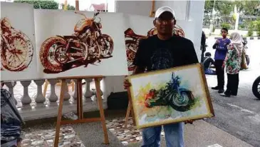 ??  ?? PEMENANG tempat pertama, Amin menunjukka­n hasil karya lukisan motosikal berkuasa tinggi yang dilukisnya secara spontan.