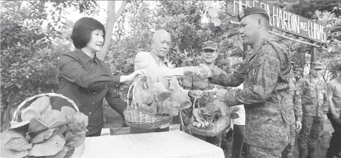  ?? (PNA) ?? VEGETABLE HARVEST FESTIVAL. Defense Secretary Delfin Lorenzana (2nd from left) and Tarlac Heritage Foundation Inc. co-founder Dra. Isa Suntay (left) distribute fresh vegetables to Army beneficiar­ies during the 2nd Hardin ng Lunas Harvest Fetivals at the Philippine Army Headquarte­rs in Fort Bonifacio, Taguig City on Wednesday (Oct. 10, 2018). Also in photo is Army commanding general, Lt. General Rolando Joselito Bautista.