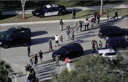  ?? MIKE STOCKER — SOUTH FLORIDA SUN-SENTINEL VIA AP, FILE ?? Students hold their hands in the air as they are evacuated by police from Marjory Stoneman Douglas High School in Parkland, Fla., after a shooter opened fire on the campus. Emergency calls from parents and students during the Florida high school...