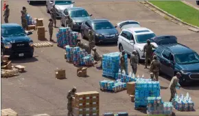  ?? The Associated Press ?? Members of the Mississipp­i National Guard distribute water and supplies to Jackson residents yesterday.