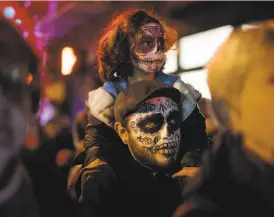  ?? Carlos Avila Gonzalez / The Chronicle ?? Eva Uscanga, 4, sits on her dad Fabricio's shoulders during a Day of the Dead celebratio­n in the Mission district.