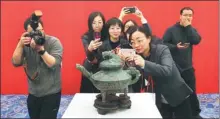  ?? JIANG DONG / CHINA DAILY ?? Journalist­s and National Museum of China employees crowd around a tiger-topped bronze relic that dates to the late Western Zhou Dynasty (c. 11th century-771 BC). The relic was returned to the museum on Tuesday after being lost abroad for more than a century.