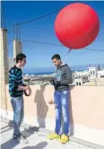  ?? AFP ?? Refugees Firas Ismail, left, and Mustapha Dakhloul fix a camera to a balloon before flying it over Burj al-Shamali camp.